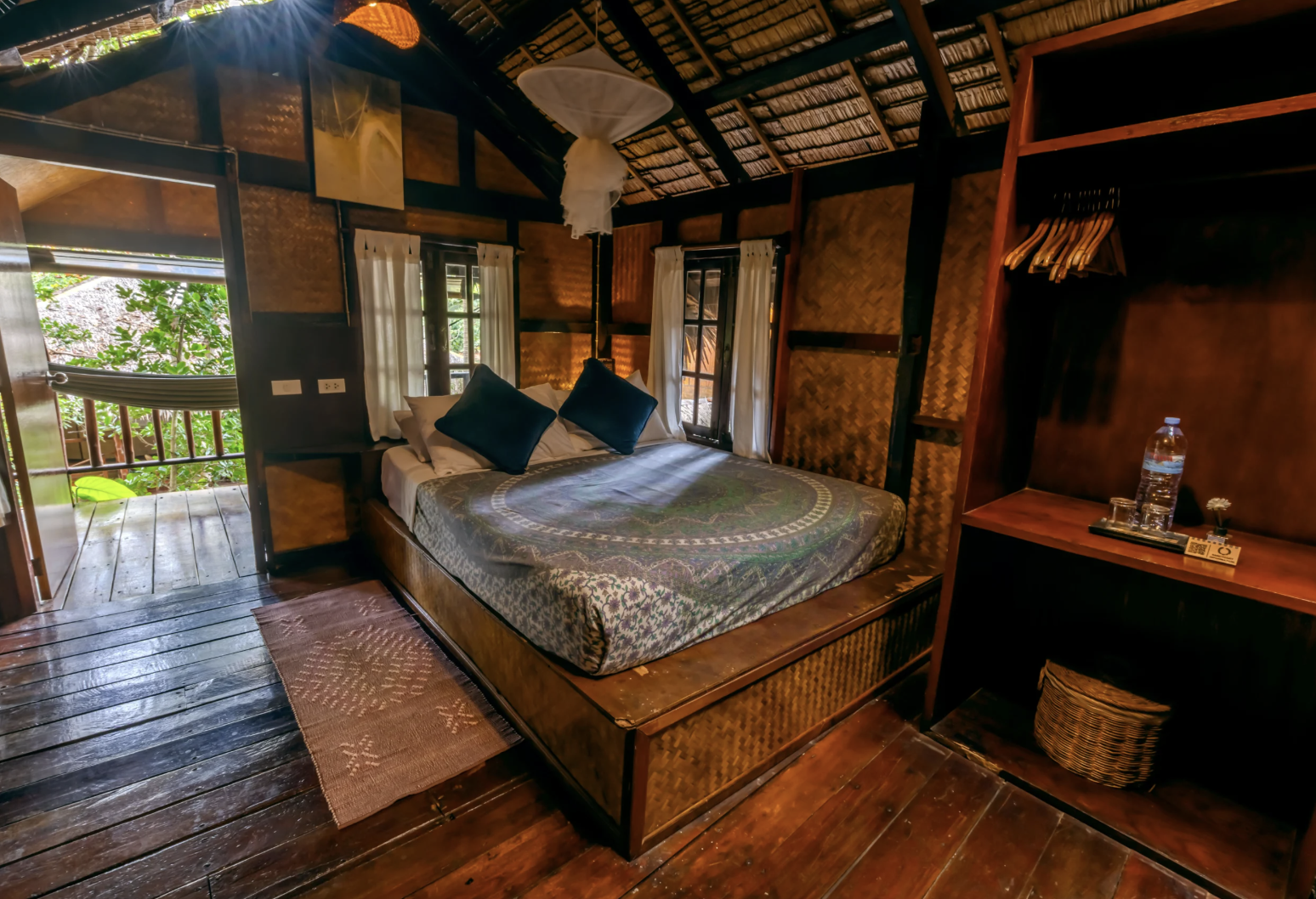 Cozy wooden bedroom with patterned bedding and an open view to the veranda