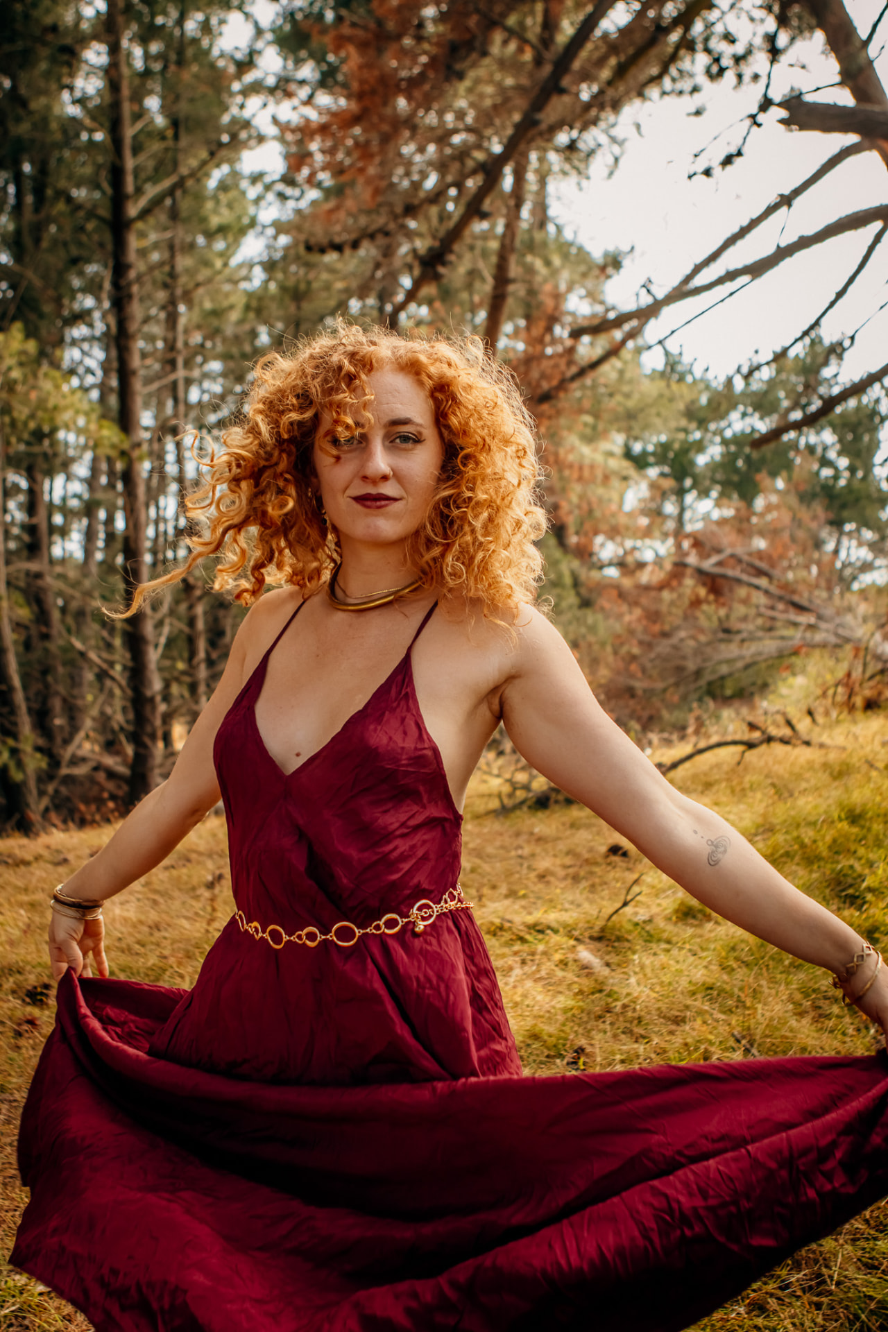 River Rose, embodiment coach and facilitator, in a red dress among the trees