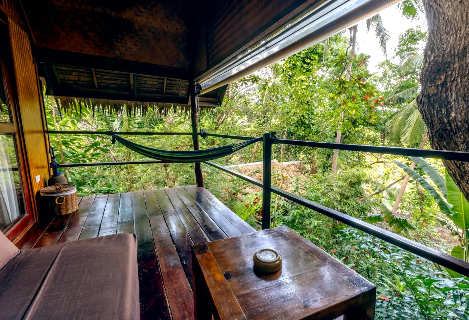 Private wooden balcony with hammock overlooking dense tropical jungle
